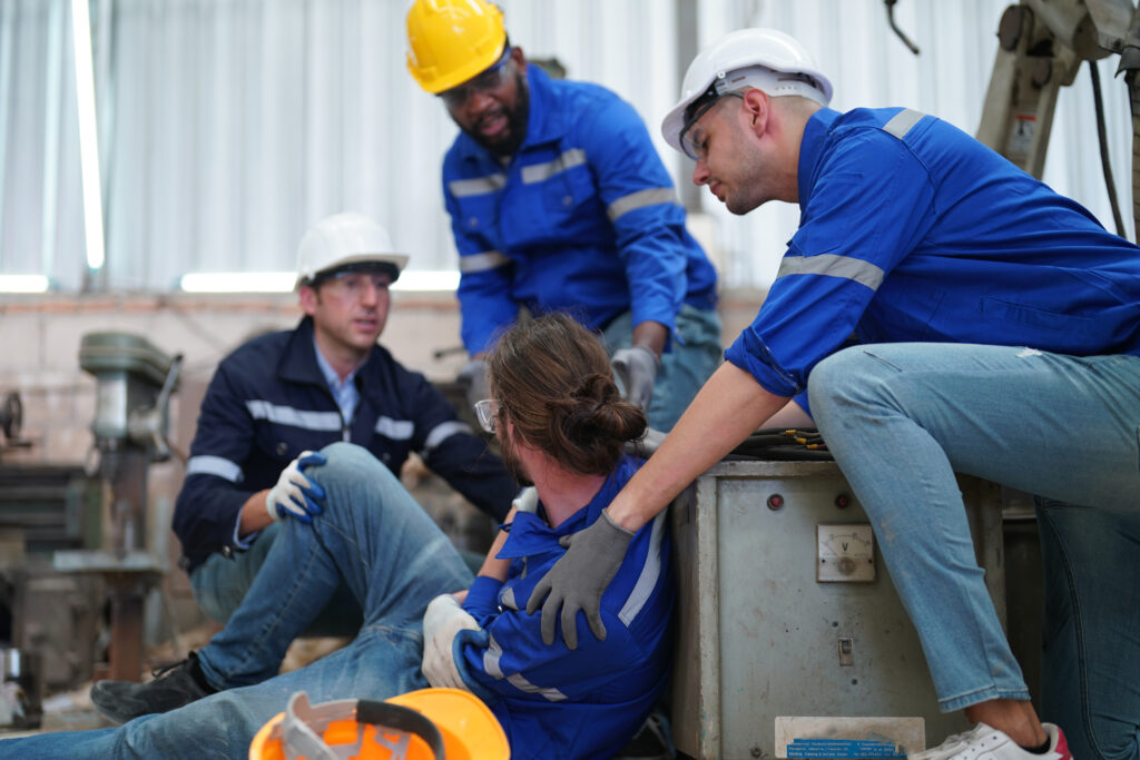 Man surrounded by coworkers holding his sholder sitting on the floor