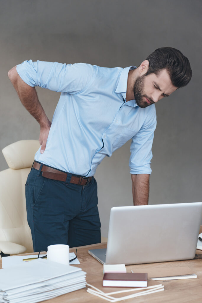 Man standing at desk with back pain