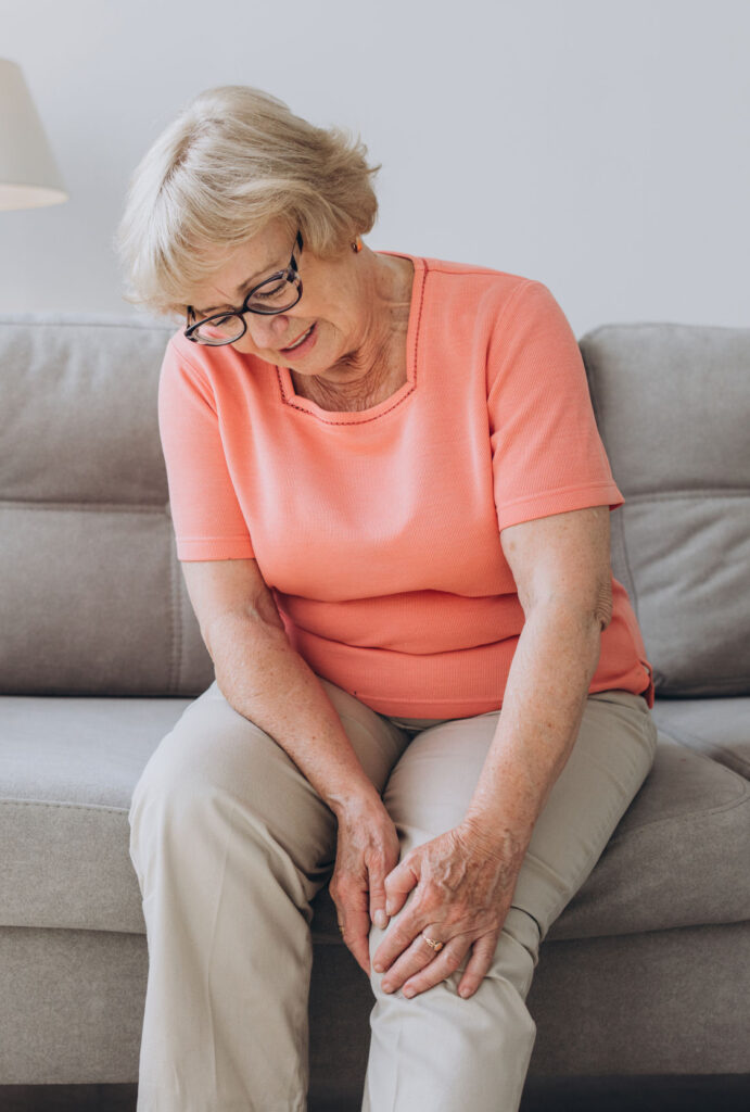 Older woman on couch holding knee