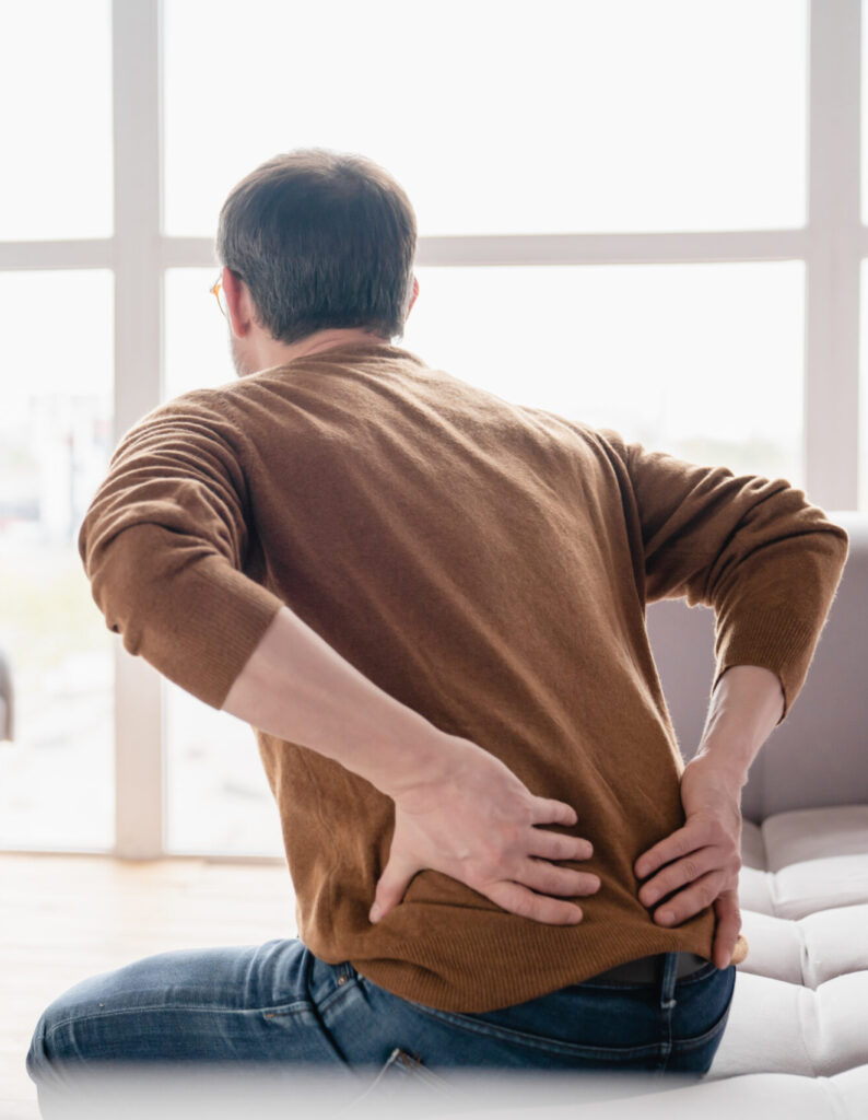 Man sitting on couch in pain from herniated disc