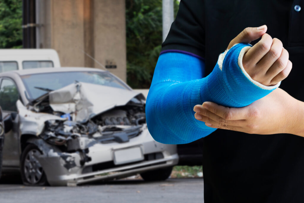 Man in front of wrecked car with injury from accident