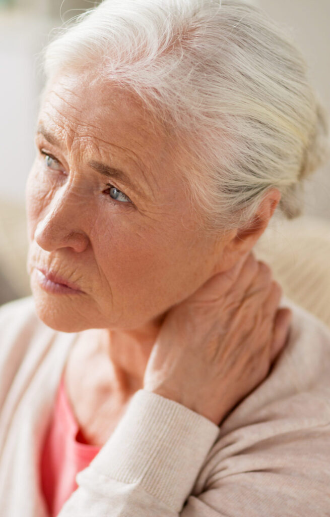 Elderly woman sitting on couch with neck pain