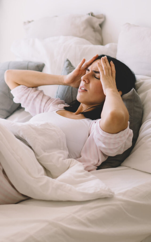 Woman laying in bed with severe migraine headache