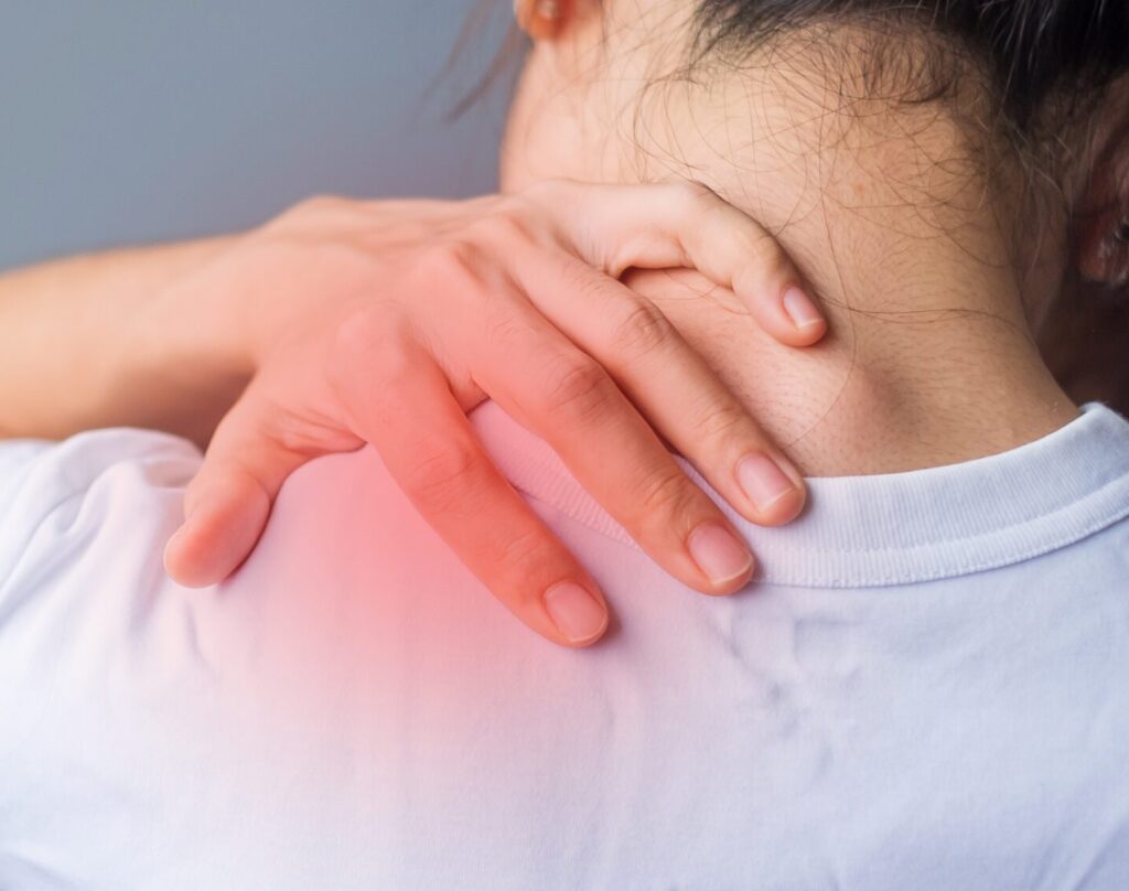 View of woman from behind holding shoulder in pain with red glow on shoulder