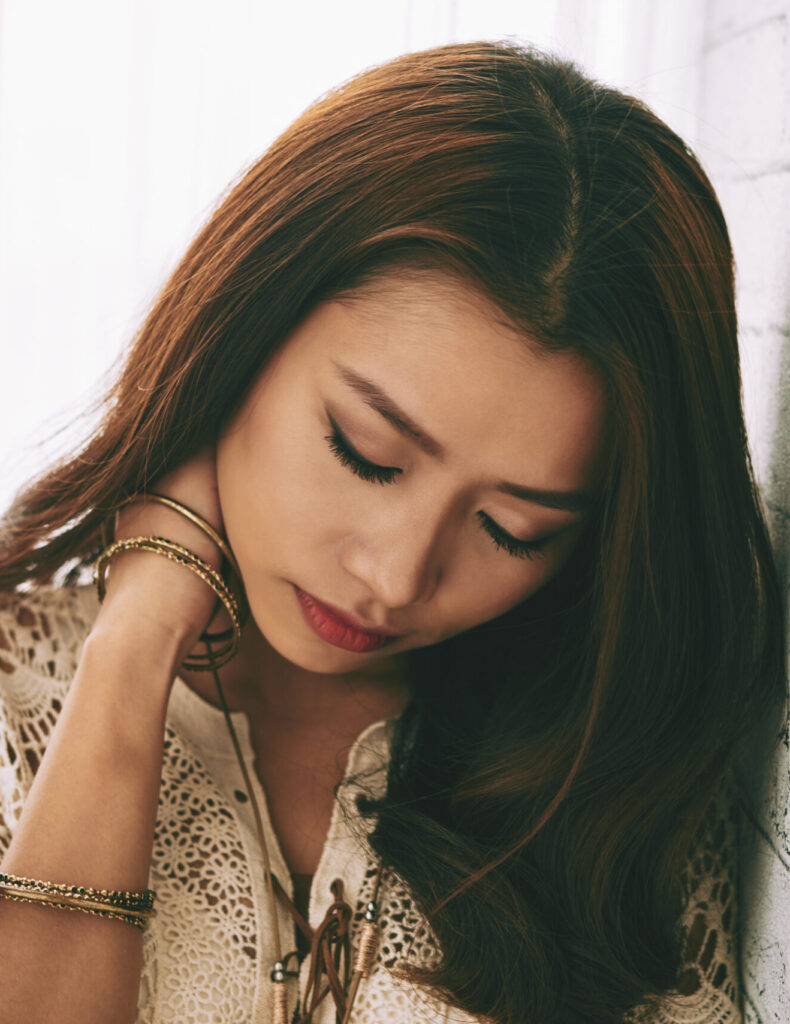 Woman leaning on wall holding neck